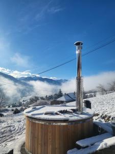 un bain à remous dans la neige avec une montagne enneigée dans l'établissement Chalet de montagne, Piscine avec vue et bain nordique, à Châteauroux-les-Alpes