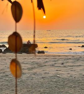 a person sitting on the beach watching the sunset at Doman Doman Eco Lodge in Gunjur