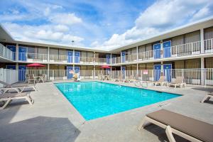 a pool in front of a hotel with tables and chairs at Motel 6 Baton Rouge Southeast in Baton Rouge
