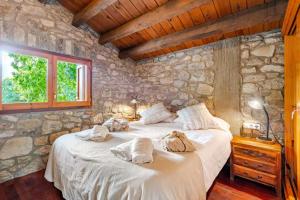 ein Schlafzimmer mit einem großen Bett in einer Steinmauer in der Unterkunft El Vilarot. La casa de piedra en la naturaleza. in Girona + 41 Fotos