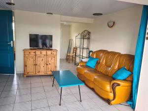 ein Wohnzimmer mit einem Ledersofa und einem TV in der Unterkunft Cottage Le pêcheur du Grand Large proximité plage in Asnelles