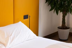 ein Schlafzimmer mit einem weißen Bett und einer Topfpflanze in der Unterkunft Tenuta Tommasi - Relais Bacco in Caorle