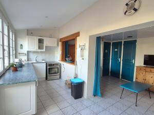 eine Küche mit weißen Geräten und blauen Vorhängen in der Unterkunft Cottage Le pêcheur du Grand Large proximité plage in Asnelles