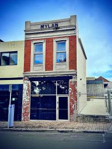 un grand bâtiment en briques avec une enseigne en mylar dessus dans l'établissement Mylan on Marine - Historic Charm, Modern Heart, à Burnie