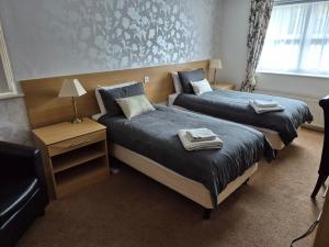 two beds in a hotel room with towels on them at Byards Leap Lodges in Welbourn +1 photo