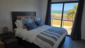 a bedroom with a bed with a view of the beach at Modern Sea and Mountain View Apartment - Gordon's Bay in Gordonʼs Bay