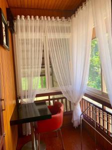 ein Balkon mit einem Tisch und einem Fenster mit weißen Vorhängen in der Unterkunft Hidden Grove 