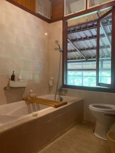 ein Badezimmer mit Badewanne und Toilette und einem Fenster in der Unterkunft Hidden Grove 