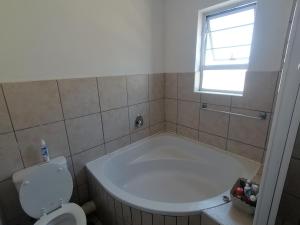 a bathroom with a tub and a toilet and a window at Luxury Living in Jbay in Jeffreys Bay +11 photos