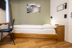 Una cama en una habitación con un escritorio y una silla en Hotel R5 Budget - Chur, en Chur