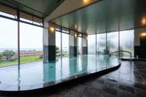 a swimming pool in a building with glass windows at Ocean Resort Nomon長崎 in Nomo