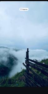 a fence on top of a hill overlooking a fog covered valley at Highrange tent camping in Vagamon