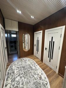 Zimmer mit zwei weißen Türen und einem Teppich in der Unterkunft Апартаменты рядом с центром in Qoraqamish