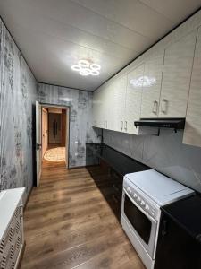 eine Küche mit weißen Geräten und Holzböden in der Unterkunft Апартаменты рядом с центром in Qoraqamish