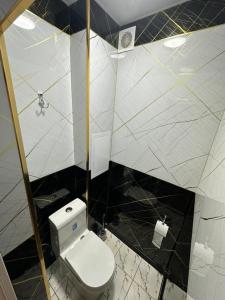 ein Badezimmer mit weißer Toilette und Dusche in der Unterkunft Апартаменты рядом с центром in Qoraqamish + 2 Fotos