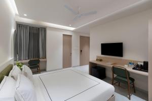 ein Schlafzimmer mit einem Bett und einem Schreibtisch mit einem Fernseher in der Unterkunft Champion Prime-My Downtown Hotel in Udaipur