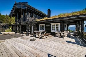 ein Haus mit einer Holzterrasse mit einem Tisch und Stühlen in der Unterkunft Log Cabin With Panoramic Views At Voss Resort in Skulestadmo