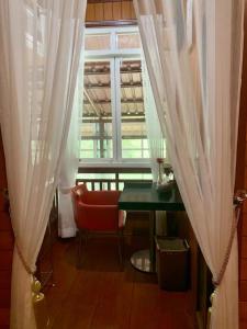 Zimmer mit einem Tisch und einem Fenster mit Vorhängen in der Unterkunft Hidden Grove  + 8 Fotos