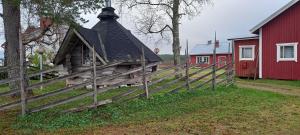 an old house with a wooden fence next to a red barn at Kotariipi in Saukkoriipi
