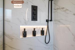 a bathroom with a shower with three bottles on a wall at 3BR House By MyStayUK Short Lets & Serviced Accommodation Manchester With Free Wifi & Free Parking in Manchester +47 photos