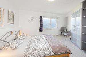 a white bedroom with a bed and a window at Casa Rondine by Fewotessin in Ronco s/Ascona - Porto Ronco +21 photos