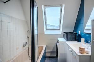 Un baño con bañera, lavabo y ventana. en Cocon Sous les Toits - Proche Centre Ville - Parking Gratuit - Commerces à Proximité, en Sélestat 27 fotos más