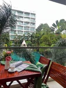 ein Holztisch auf einem Balkon mit Blick auf ein Gebäude in der Unterkunft Club Royal C324 in Pattaya North