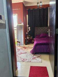 una camera con letto viola e pareti rosse di استديو لشخصين ad Ajman