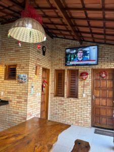 a room with a brick wall with a tv on the wall at Chalés 4 Estações in Beberibe
