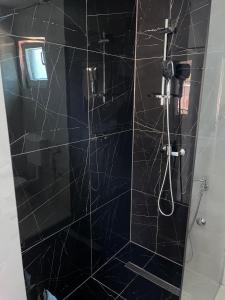 baño con ducha de azulejos negros en Vila Ayla, en Blagaj 1 foto más