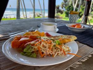 une assiette de nourriture sur une table avec un sandwich et une salade dans l'établissement Rella Dream, à Matara