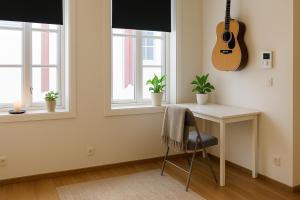 een bureau en een gitaar in een kamer met ramen bij Cottage studio in city centre in Tromsø +4 foto's