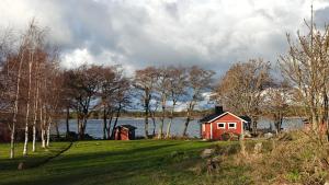 a red house on a field next to a lake at Sandholm Cottage in Nötö +46 photos