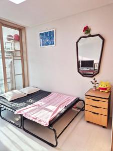 a bed in a room with a mirror and a dresser at Healing Gangchu in Anyang