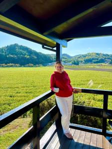 Una donna in piedi su una recinzione di fronte a un campo di Setouchi Retreats Sera Highlands 