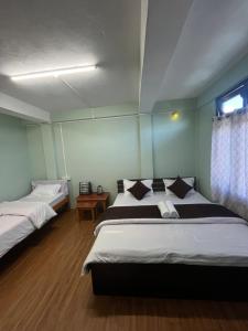 ein Schlafzimmer mit zwei Betten und einem Fenster in der Unterkunft Hotel Tashi Tseleng in Tawang