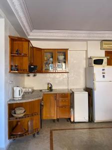 eine Küche mit Holzschränken und einem weißen Kühlschrank in der Unterkunft Appartement en plein cœur de Marrakech in Marrakesch