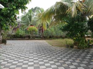 a courtyard with a checkered floor and palm trees at Temple Courtyard in Chengannūr