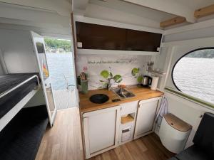 eine Küche in einem Wohnwagen mit Spüle und Fenster in der Unterkunft Hausboot Rollyboot Evolution 2- feste Unterkunft am Steg in Joachimsthal