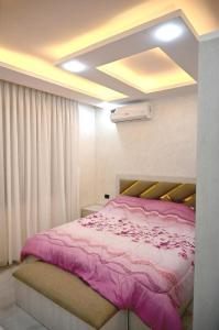 une chambre avec un lit avec une couverture rose dans l'établissement For daily, weekly monthly and yearly stays, à Amman