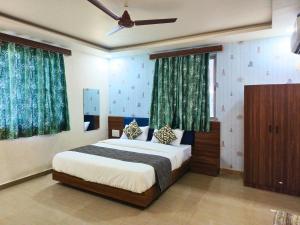 a bedroom with a bed and a ceiling fan at Hotel Shree Maya Inn in Vadodara