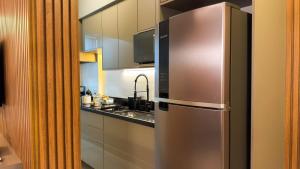 a kitchen with a stainless steel refrigerator and a sink at Apartamento com aconchego e modernidade Apogeo in Ribeirão Preto