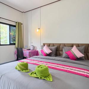 a bedroom with a bed with two green towels on it at Khao Sok Backpacker Hostel in Khao Sok National Park