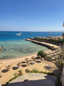 a beach with umbrellas and chairs and the ocean at Dive Hostel Hurghada Beach in Hurghada