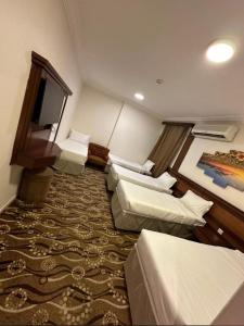 Cette chambre comprend 3 lits et une télévision à écran plat. dans l'établissement فندق الزائر الأخيار الفندقية, à La Mecque