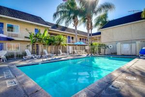 einem Pool vor einem Gebäude mit Palmen in der Unterkunft Motel 6-Riverside, CA - South in Riverside