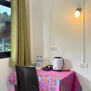 a table with a pink table cloth and a tea kettle on it at Khao Sok Backpacker Hostel in Khao Sok