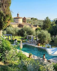 Una piscina en un jardín con una casa al fondo. en CASA VASARI Holiday Suites TUSCANY, en Lucignano