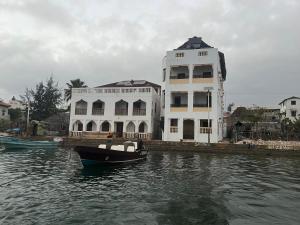 a large white building with a boat in the water at Mafazy House in Lamu