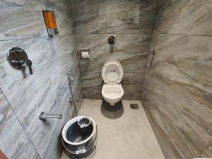 een badkamer met een toilet en een vuilnisbak bij Hotel Melody Boutique Thane in Thane